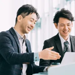 ノートパソコンを前に笑顔で話す二人の男性